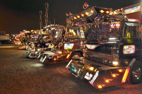 Japan Trucks
Dekotora-Disco: Aufgereiht und bereit fÃ¼r die groÃŸe Show stehen zehn und mehr Trucks bei Events nebeneinander und synchronisieren ihre Lightshow, Musik und Sounds. Beim dritten von rechts fallen Takelagen auf, an denen Banner angebracht werden kÃ¶nnen.
