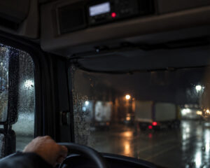 Lkw-Fahrerhaus bei Nacht und Regen, oben in der Dachkonsole der Fahrtenschreiber mit roter Leuchte
