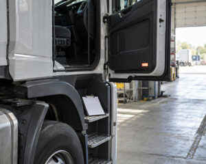Lkw-Zugmaschine in einer Prüfhalle, Fahrertür offen, Klemmbrett auf dem Trittbrett