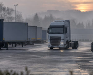 Lkw-Zugmaschine rangiert am frühen Morgen auf einem Betriebshof zwischen abgestellten Aufliegern