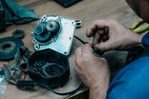 Techniker repariert ein mechanisches Getriebe auf einem Holztisch in einer Werkstatt.