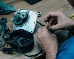 Techniker repariert ein mechanisches Getriebe auf einem Holztisch in einer Werkstatt.