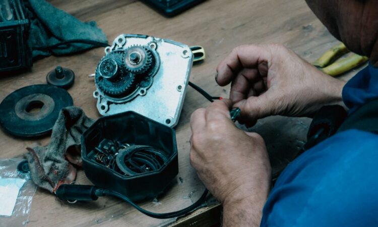 Techniker repariert ein mechanisches Getriebe auf einem Holztisch in einer Werkstatt.