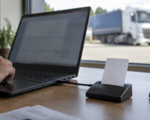 Laptop mit USB-Chipkartenleser und eingesteckter Karte, im Hintergrund ein Lkw