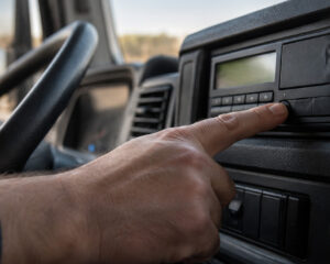 Finger drückt eine Taste am digitalen Fahrtenschreiber im Lkw-Fahrerhaus