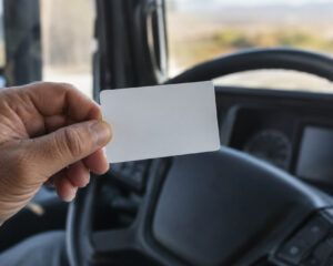 Hand hält eine Karte vor dem Lenkrad eines Lkw